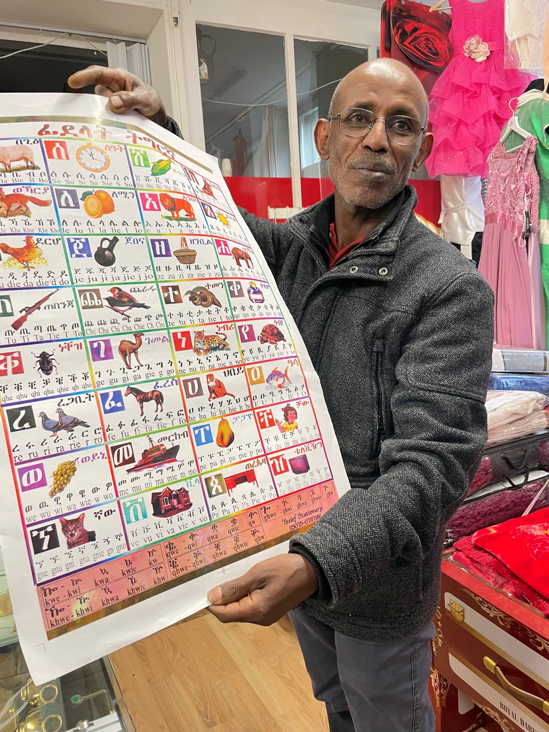 Mann zeigt ein Poster mit Buchstaben und Tieren in einem Laden
