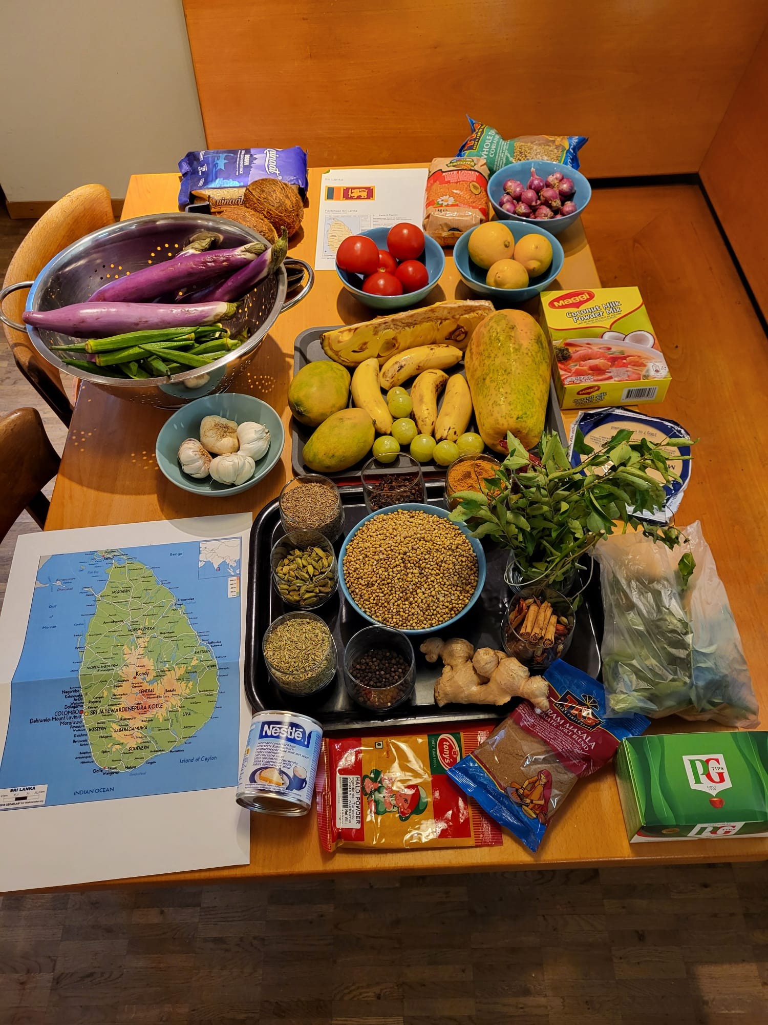 Tisch voller Zutaten aus Sri Lanka mit Gemüse, Früchten, Gewürzen und einer Landkarte